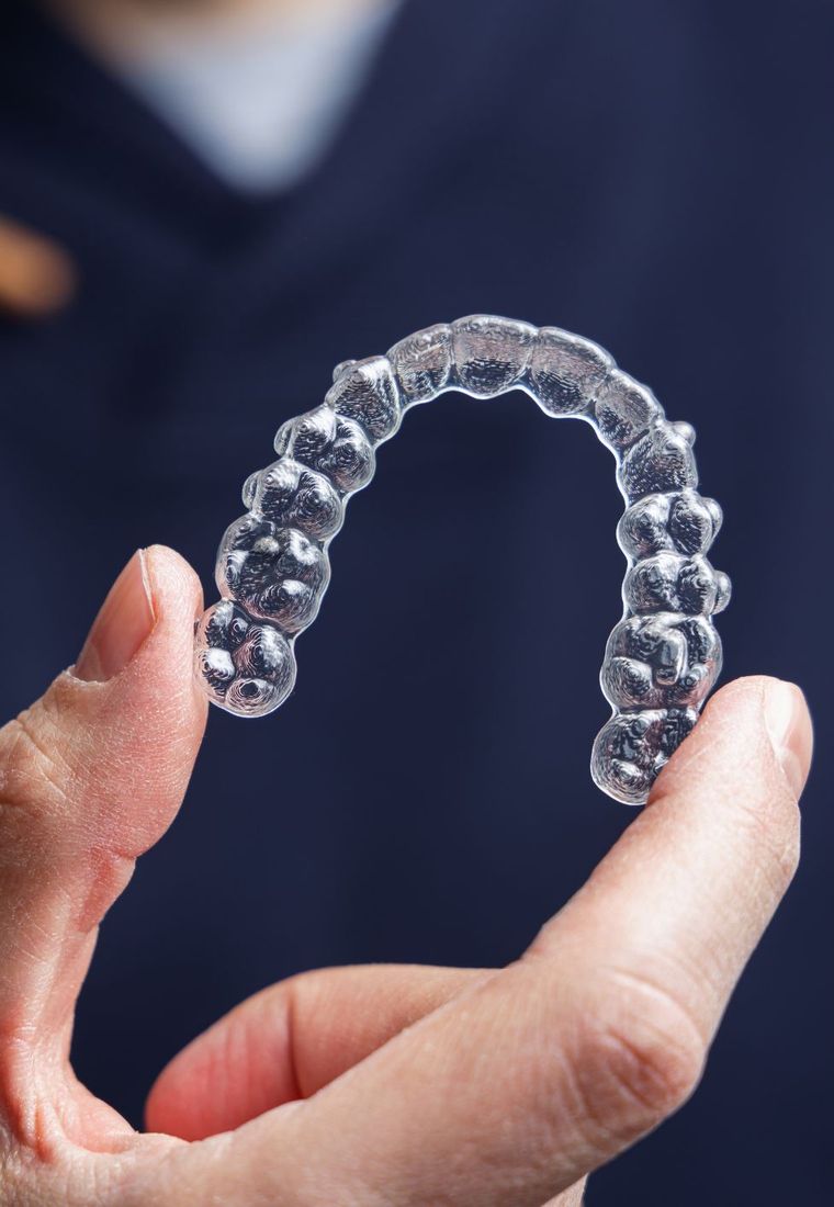 A clinician holding a discreet, removable Invisalign clear aligner